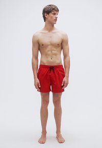 Κόκκινα μαγιό βερμούδα με ελαστική μέση και κορδόνι, κατασκευασμένα από ελαφρύ υλικό. Σχεδιασμένα για άνεση και ευκινησία.