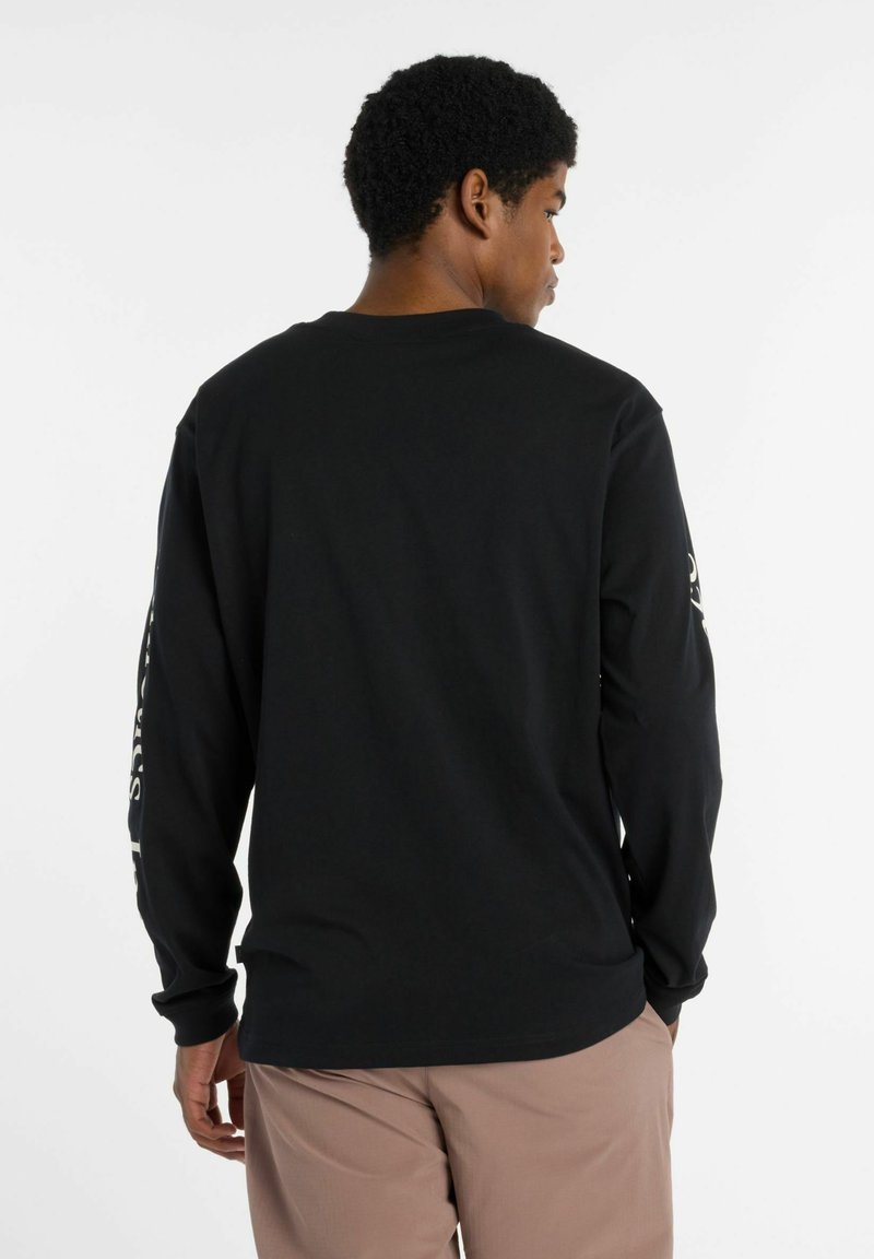 Zwarte langarmshirt met een ronde hals en witte tekstdetails op de linkermouw. Gemaakt van zacht katoen.