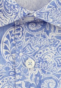 Gros plan du col et des boutons d'une chemise à motif floral bleu et blanc avec des dessins détaillés de feuilles et de volutes.