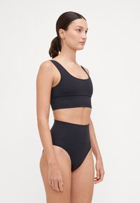 Fekete, két részből álló fürdőruha, amely egy fitted crop topból áll széles pántokkal és magas derekú alsóból, mindkettő sima, rugalmas anyagból készült.