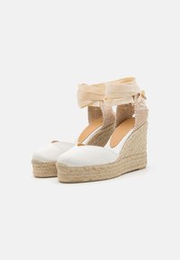 Espadrillas con zeppa in canvas bianco e suola in corda di juta, dotate di una cinghia alla caviglia in tessuto intrecciato e lacci di raso beige chiaro.