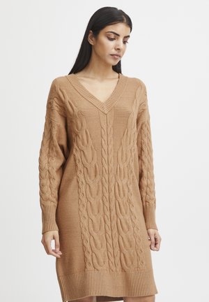 Kabelstrickkleid in Hellbraun. Mit V-Ausschnitt, langen Ärmeln, gerippten Bündchen und einem strukturierten Muster an der Vorderseite.