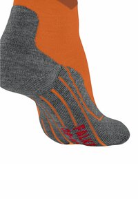 Primo piano di una calza alla caviglia arancione e grigia con tallone e suola rinforzati, che mostra la lavorazione a maglia testurizzata e il testo del marchio rosso sulla suola.