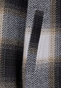 Gyapjú keverék szövet, fekete, bézs és fehér houndstooth mintával. Zsebet tartalmaz, valamint texturált felülete van, amely különböző szövéseket mutat.