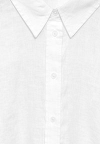 Camicia bianca in lino con colletto a punta e chiusura frontale con bottoni. Tessuto morbido con un lieve motivo intrecciato. I bottoni sono rotondi e trasparenti.