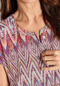 Kurzärmelige Bluse mit einem mehrfarbigen Zickzackmuster, runder Halsauschnitt mit Knopfdetail und leichtem, strukturiertem Stoff.