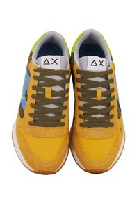 Zapatillas de hombre con una parte superior de ante y tela en color amarillo, cordones en verde oliva, acentos en azul y una suela blanca. Presenta detalles de costura y logotipos.