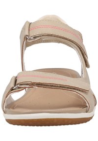 Sandali beige con due cinturini regolabili in velcro, cuciture rosa, punta aperta, suola imbottita e suola in gomma con texture.