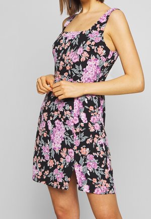 Robe noire à motifs floraux avec de grandes fleurs roses et violettes, encolure carrée, larges bretelles et une fente à l'avant, confectionnée dans un tissu léger.