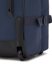 Valigia a mano blu navy con tessuto testurizzato, angoli rinforzati e una grande ruota nera per la mobilità. Include una cinghia laterale.