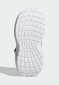 Bílá podrážka tenisky s texturovaným gripem, s zaoblenou patou a centrálním žlábkem pro flexibilitu, vyrobená z odolného gumového materiálu.