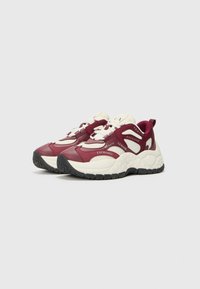 Chaussures de sport bordeaux et crème au design chunky, avec une semelle texturée et des accents de marque. Fermeture à lacets et col rembourré.