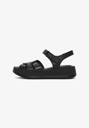 Sandales en cuir noir avec un design à plateforme, présentant des sangles croisées et une sangle arrière pour le soutien. Semelle en caoutchouc noir uni.