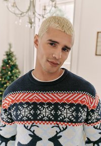 Pulover tricotat de culoare bleumarin cu modele geometrice multicolore. Prezintă motive cu reni, guler rotund și un finisaj texturat.