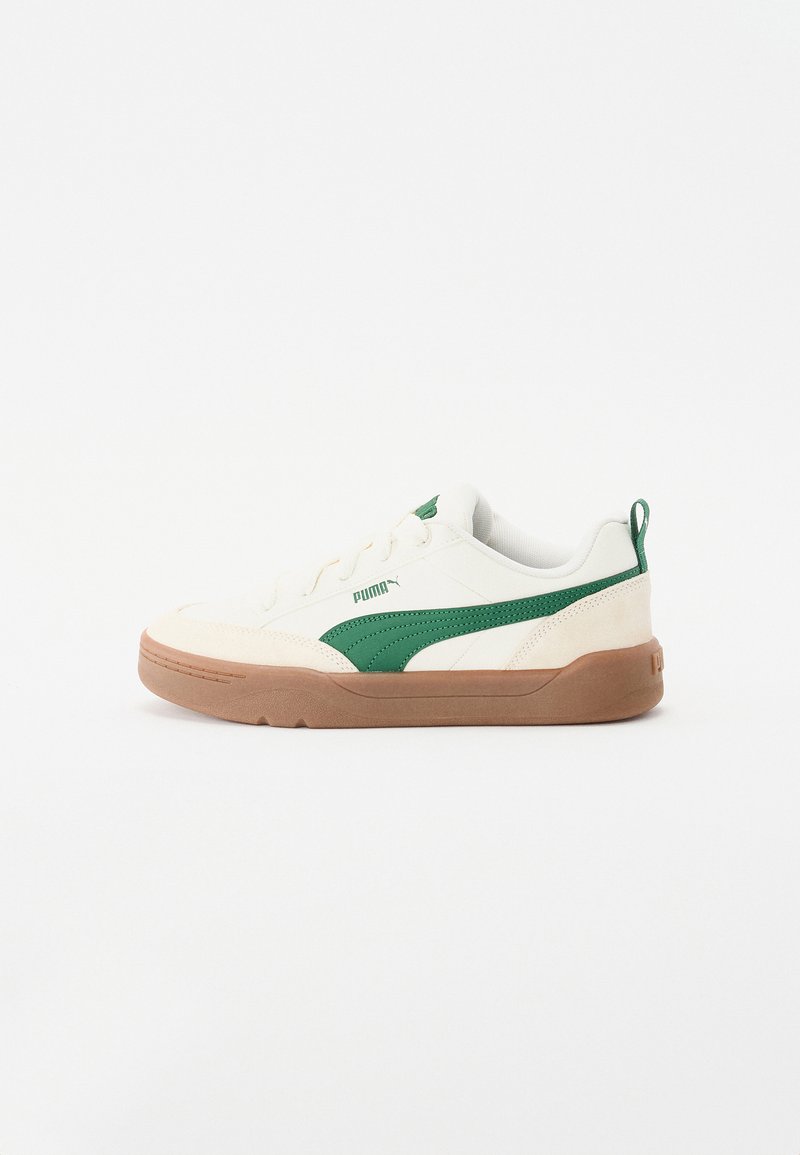 Hvite sneakers med grønne detaljer, overdel i semsket skinn og tekstil, rund tå, teksturert såle og merkevarelogo på siden og hælen.