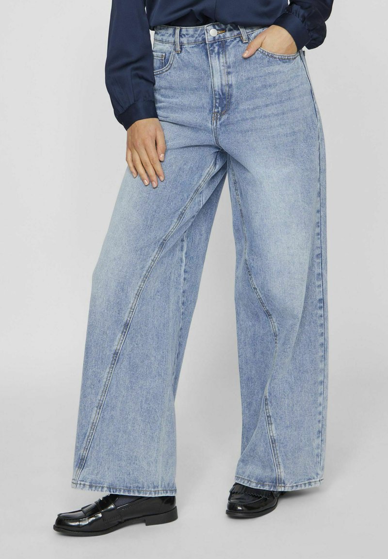 Jeans de pierna ancha en denim azul claro, con una cintura alta, corte recto, detalles de costura sutiles y un diseño clásico de cinco bolsillos.