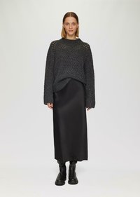 Grijze gebreide trui met lange mouwen, open stiksel ontwerp, gecombineerd met een zwarte satin maxi rok en zwarte chunky laarzen. Minimalistische esthetiek.