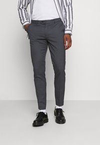 Grå stribede bukser med slim fit, der har knaplukning og sidelommer, parret med sorte sko og hvide sokker.