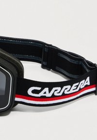 Häkkide prillid matte musta raamiga, tumedate läätsedega ja musta rihmaga, millel on valge tekst "CARRERA" ning punased ja valged triibud.
