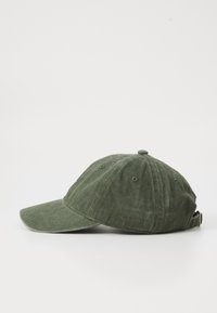 Căciulă de baseball din material verde, cu o margine curbă, având șase orificii de ventilație și o curea ajustabilă în spate.