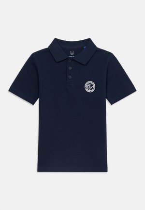 Polo de manga corta azul marino con tapeta de tres botones y un pequeño logo circular blanco en el pecho izquierdo.