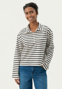Ribadest pehmest kangast kootud pullover, millel on lukuga kaelus, pikad varrukad ja rinnakott. Värvid on kreemjasvalged ja mustad triibud.