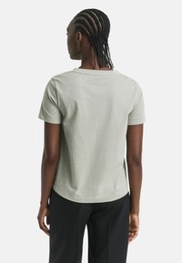 Hellgrünes T-Shirt mit kurzen Ärmeln und rundem Ausschnitt, in lockerer Passform, aus weichem Stoff, von hinten gezeigt.