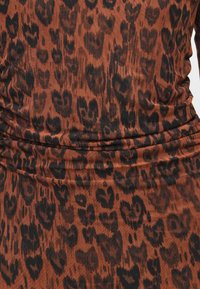 Leopardi mustriga kangas pruunide ja mustade tooni, millel on pehme, tekstureeritud pind koos kogutud detailidega.