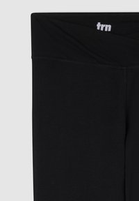 Leggings neri in tessuto elasticizzato. Presentano una cintura larga con il logo bianco "trn". Tessuto liscio e design aderente con cuciture piatte.