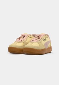 Suede sneakers in yellow and light pink, featuring a rubber sole, rounded toe, flat laces, and "PUMA" branding on the side.