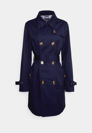 Trench-coat croisé bleu marine avec boutons marron, taille ceinturée, col et brides à boucle sur les manches longues.
