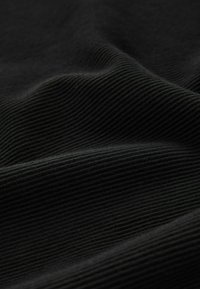 Tessuto nero a costine con una consistenza morbida, caratterizzato da linee parallele che corrono orizzontalmente sulla superficie, creando un motivo sottile.