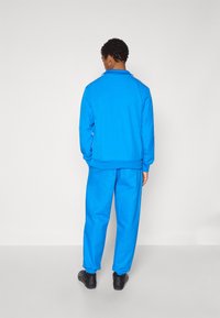 Σετ μπλε φούτερ και φόρμας από απαλό βαμβάκι. Διαθέτει γιακά, ριμπ μανσέτες και αντίθετη ραφή στους ώμους.