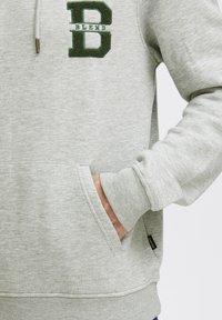 Gray hoodie featuring a prominent green embroidered "B" logo and the word "BLEND." Includes a front pocket and ribbed cuffs.