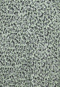 Svart- och vitfjärilsdesign på ljusgrön tyg. Textilen har en delikat struktur med ett mjukt, lätt utseende.