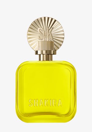 Gelbe quadratische Parfümflasche mit abgerundeten Kanten, geprägt mit dem Schriftzug "SHAKIRA", und einem gold geriffelten, runden Verschluss mit Sonnenstrahl-Design und den Initialen "SK".