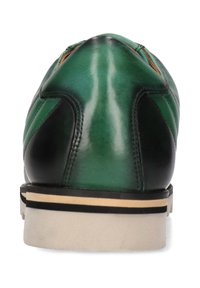 Grüner und schwarzer Lederschuh mit runder Spitze, der eine strukturierte Oberfläche, eine kontrastierende weiß-schwarze Sohle und minimale Akzentdetails aufweist.