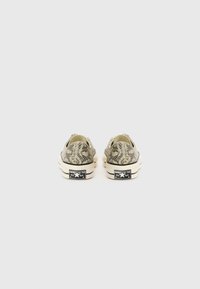 Zöld és fekete kígyómintás vászon slip-on cipők, klasszikus fehér gumitalppal, kontrasztos fekete sarokapplikációkkal, amelyeken márkajelzés található.