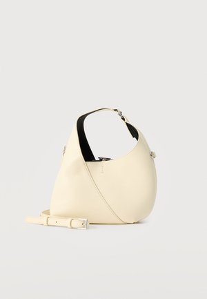Sac hobo en cuir couleur crème avec une poignée courte, des ferrures argentées et une bandoulière amovible et réglable sur fond blanc.
