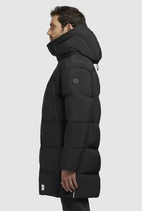 Giubbotto puffo nero con colletto alto, tasche frontali con zip e materiale impermeabile. Cappuccio con lacci regolabili.