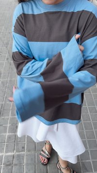 Langärmliges Hemd mit abwechselnd hellblauen und braunen Streifen, in lässiger Passform und breiten Manschetten. Kombiniert mit einem weißen Rock und schwarzen Sandalen.