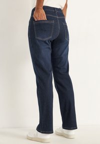 Mörkblå denimbyxor har en rak benklippning, bakfickor, kontrasterande sömmar och en subtil texturerad finish.