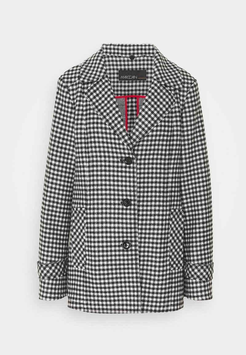 Sort-hvid hundetandsmønstret blazer med spids revers, to forlommer og fire sorte knapper. Har en rød accent indvendig foring.