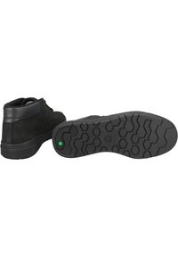 Zapatos de media caña negros hechos de ante con una suela de goma texturizada que presenta un patrón de desgaste hexagonal. Incluye un detalle del logo en verde en la suela.