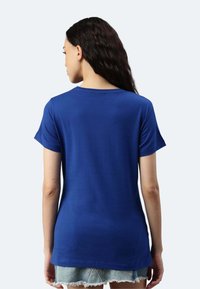 T-shirt in cotone blu con maniche corte, scollatura rotonda e vestibilità rilassata. Il retro è semplice e il tessuto appare liscio con una leggera lucentezza.