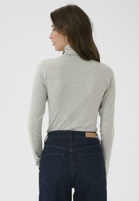 Halli kaelusega pikakä sleeves topp pehmest kangast, koos kõrge vöökoha tume denimpükstega, millel on tagakotid ja sildipatch.