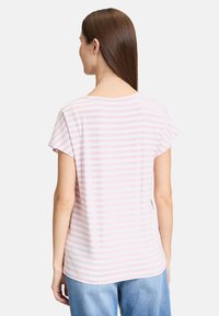 Chemise rayée à manches courtes en rose clair et blanc. Tissu doux, col rond, et coupe décontractée avec un ourlet arrondi à l'arrière.