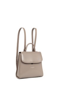 Sac à dos en cuir beige avec une forme structurée, une poignée supérieure, des bretelles réglables et un rabat avant. Présente un logo de marque à l'avant.