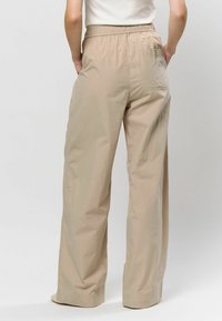 Béžové, s vysokým pásom, široké nohavice s ľahkou textúrou. Obsahujú elastický pás a zadnú vrecko.