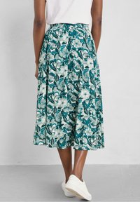 Kwiatek midi spódnica w turkusowym i zielonym materiale. Posiada dopasowaną talię, fałdy i lekką strukturę. W zestawie z białymi trampkami.